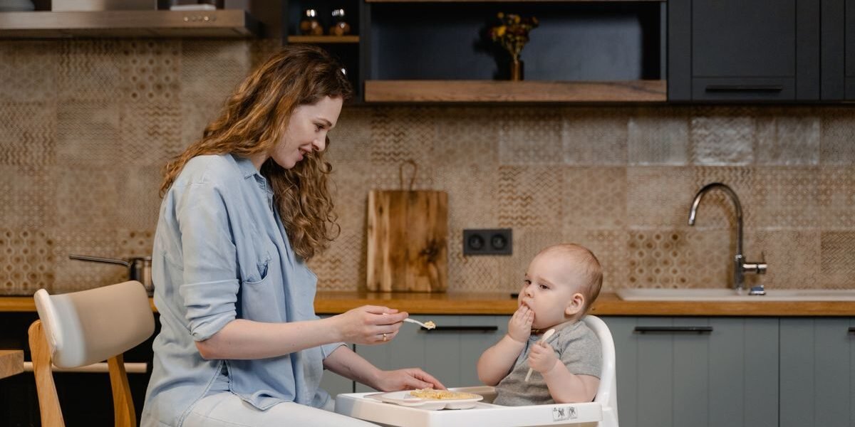 Baby van zes maanden in houten meegroeistoel aan de eettafel