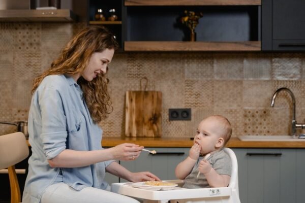 Baby van zes maanden in houten meegroeistoel aan de eettafel