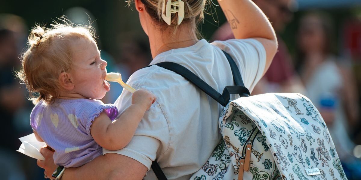 Vader draagt luiertas rugzak met baby in draagzak