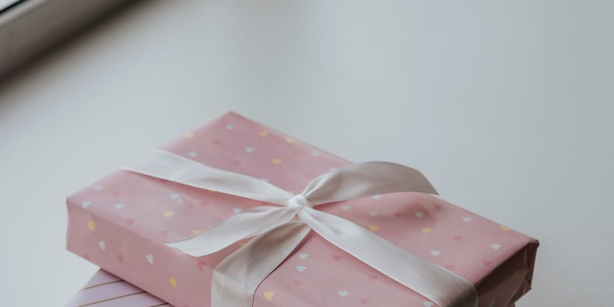 Origineel baby cadeau: ingepakt pakje met maandkaarten en houten speelboog