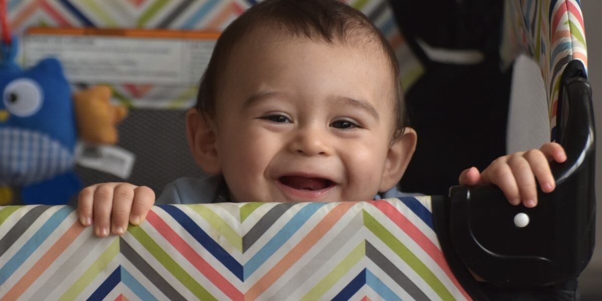 Lachende baby in een reisbedje dat ook als box dient