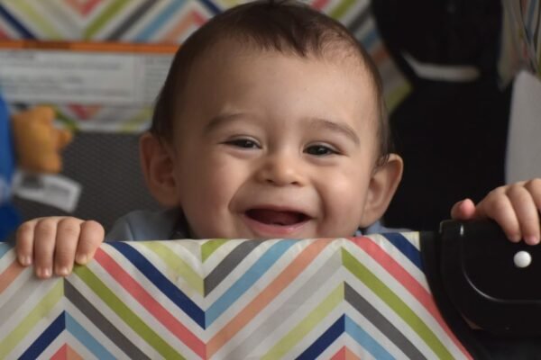 Lachende baby in een reisbedje dat ook als box dient