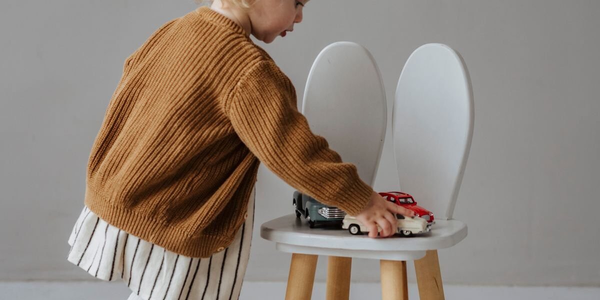 Wit houten stoeltje met geboortekaartje bedrukt op de rugleuning