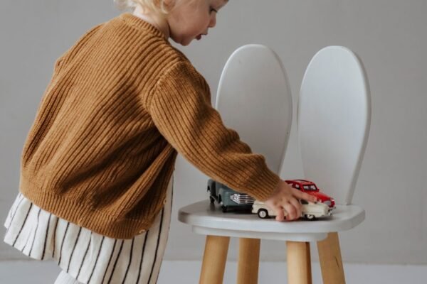 Wit houten stoeltje met geboortekaartje bedrukt op de rugleuning