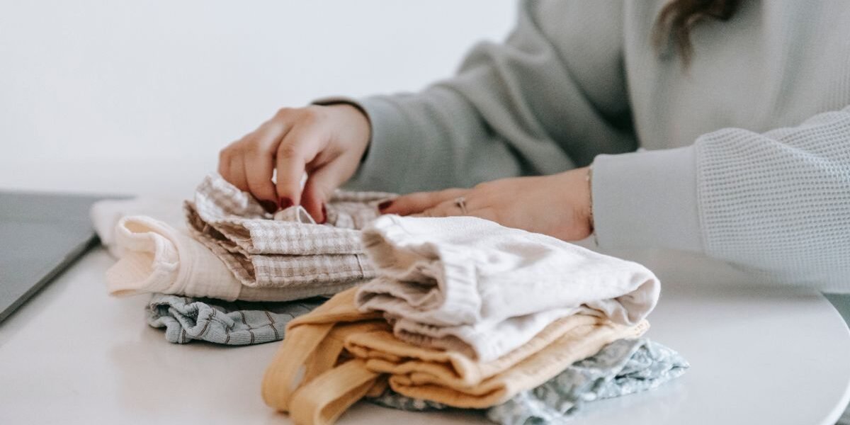 Tips baby uitzet: babykleding per maat gesorteerd op een commode