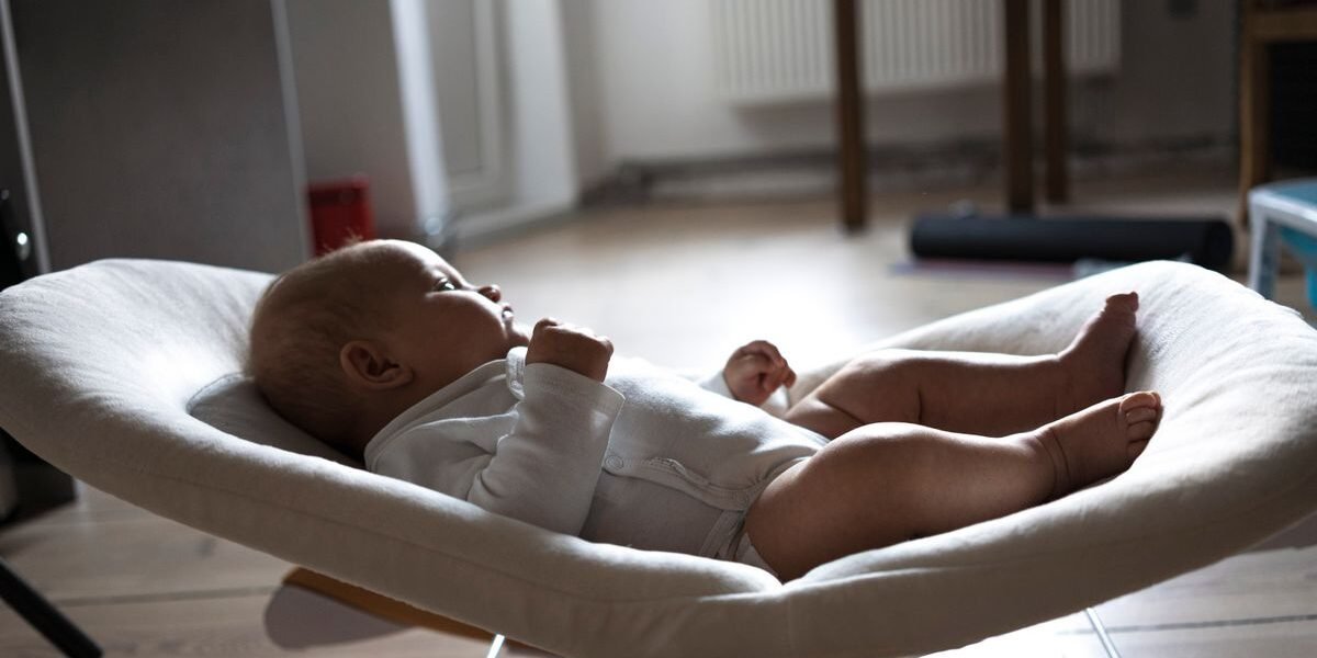 Baby ligt in een wipstoel in de woonkamer