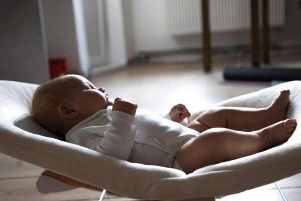 Baby ligt in een wipstoel in de woonkamer