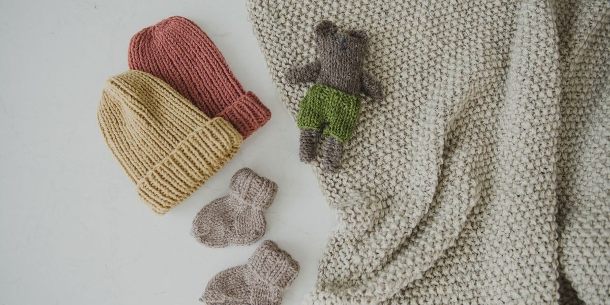 Baby in merinowollen romper en muts, wollen dekentje ernaast