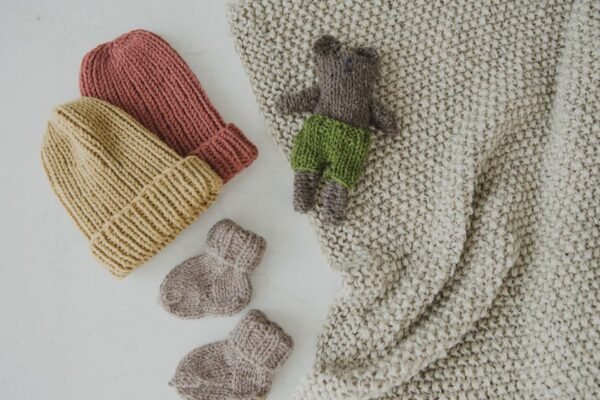 Baby in merinowollen romper en muts, wollen dekentje ernaast