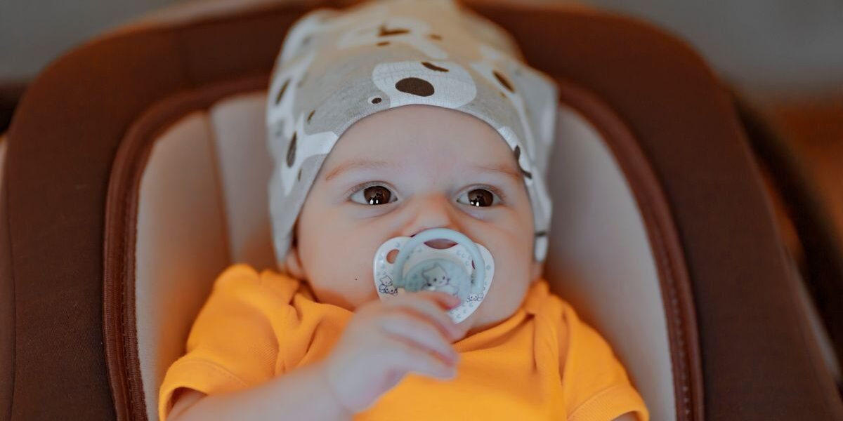 Moeder lacht naar haar baby in een autostoel in de auto