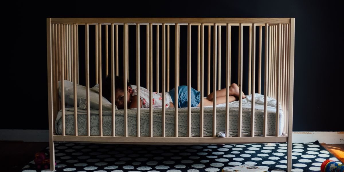 Babykamer verduisteren: houten ledikant naast een raam met gordijnen