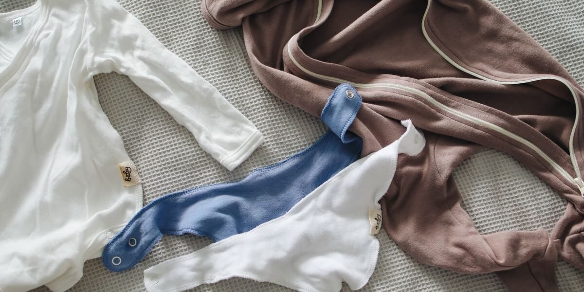 Kleine katoenen pakjes en slabbetjes voor de babyuitzet op bed