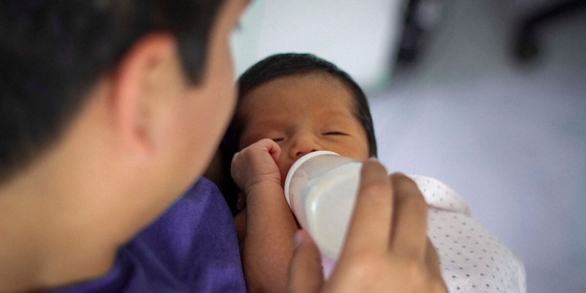 Vader geeft pasgeboren baby een fles naast de borstvoeding