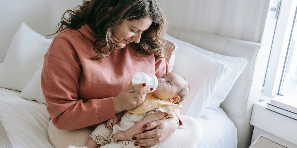 Glimlachende mama geeft haar pasgeboren baby flesvoeding