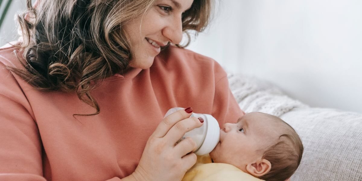 Mama geeft haar baby vers bereide flesvoeding in de woonkamer