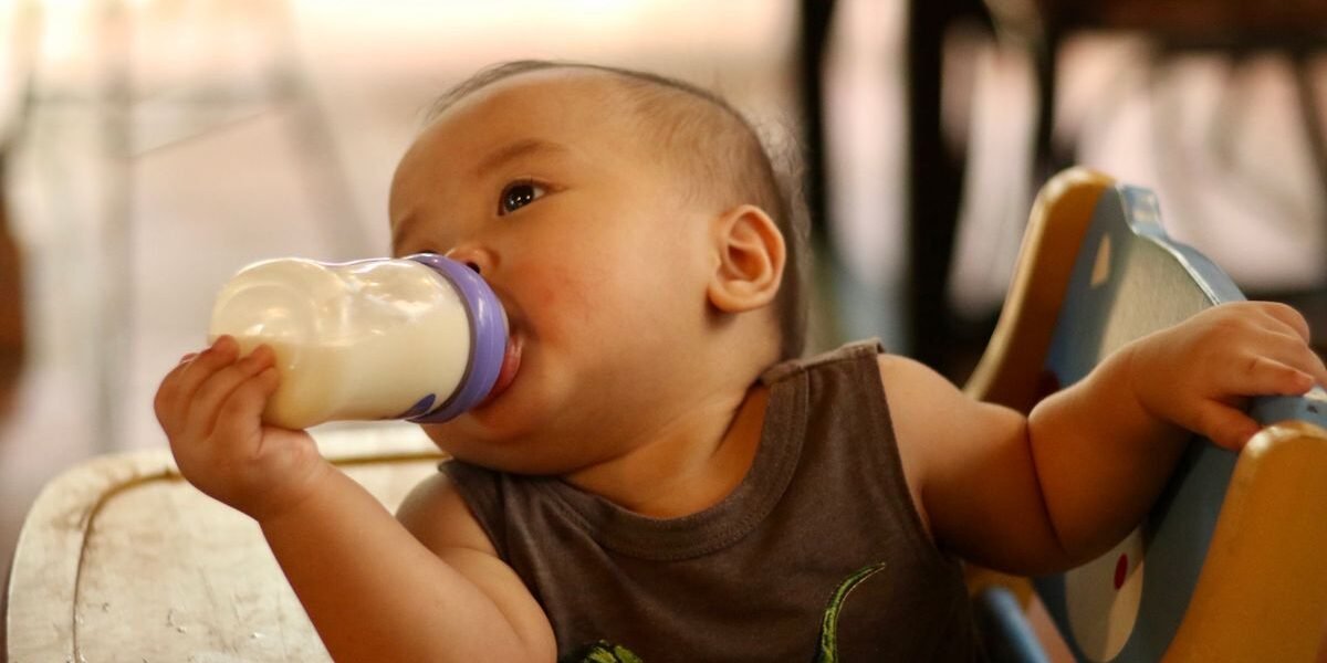 Babyfles voor flesvoeding op een kinderstoel in het daglicht