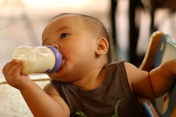 Babyfles voor flesvoeding op een kinderstoel in het daglicht