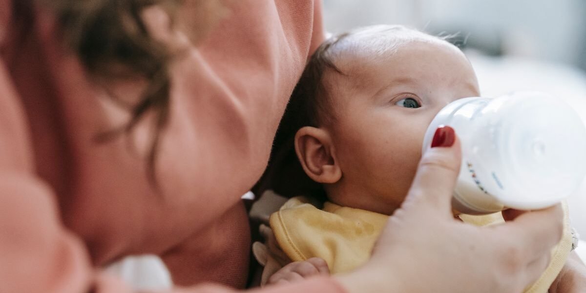 Mama geeft haar baby een flesje, deel van de babyuitzet