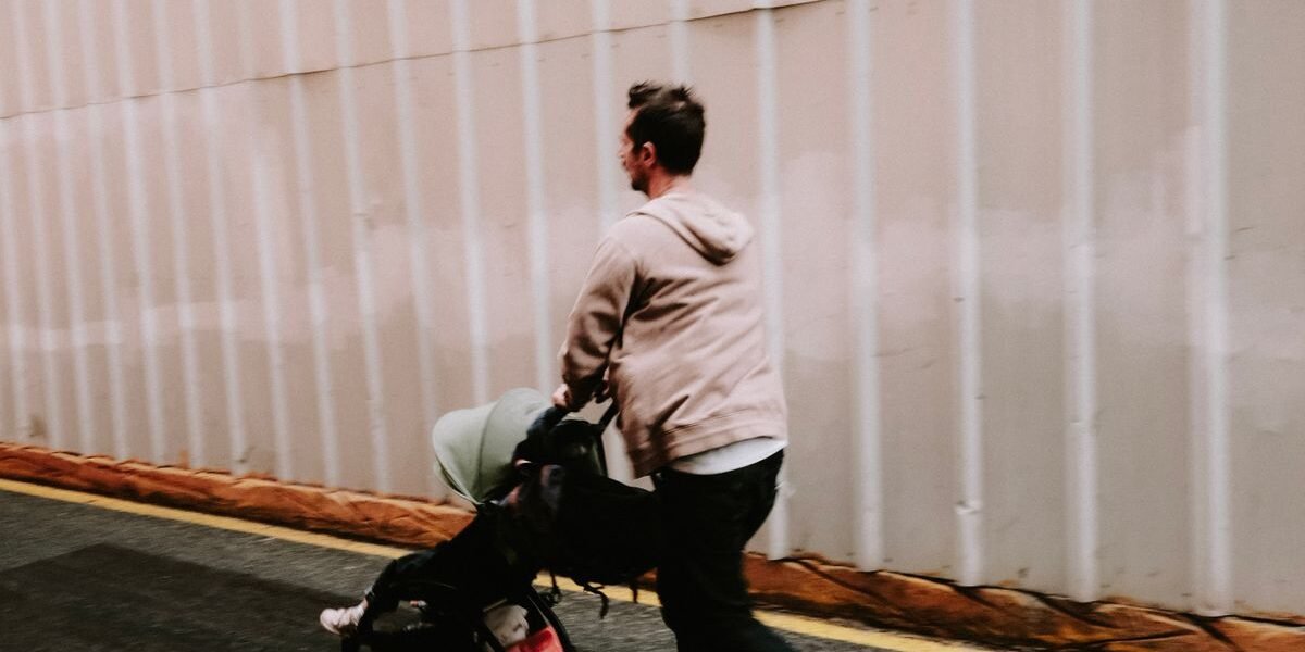Koppel wandelt met kinderwagen over een landweg in de zon