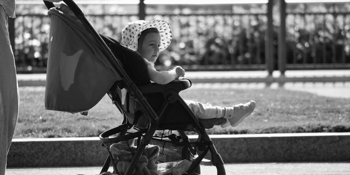 Moeder lacht naar haar baby in de kinderwagen, wanneer uit de bak