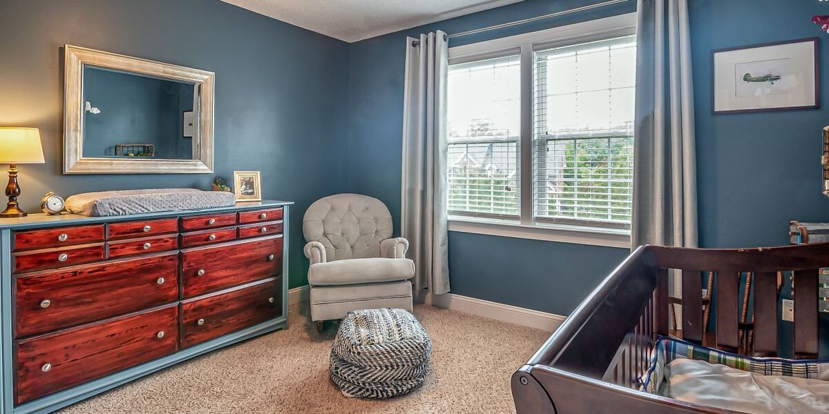 Kleine babykamer ingericht met een fauteuil in de hoek en een ledikant