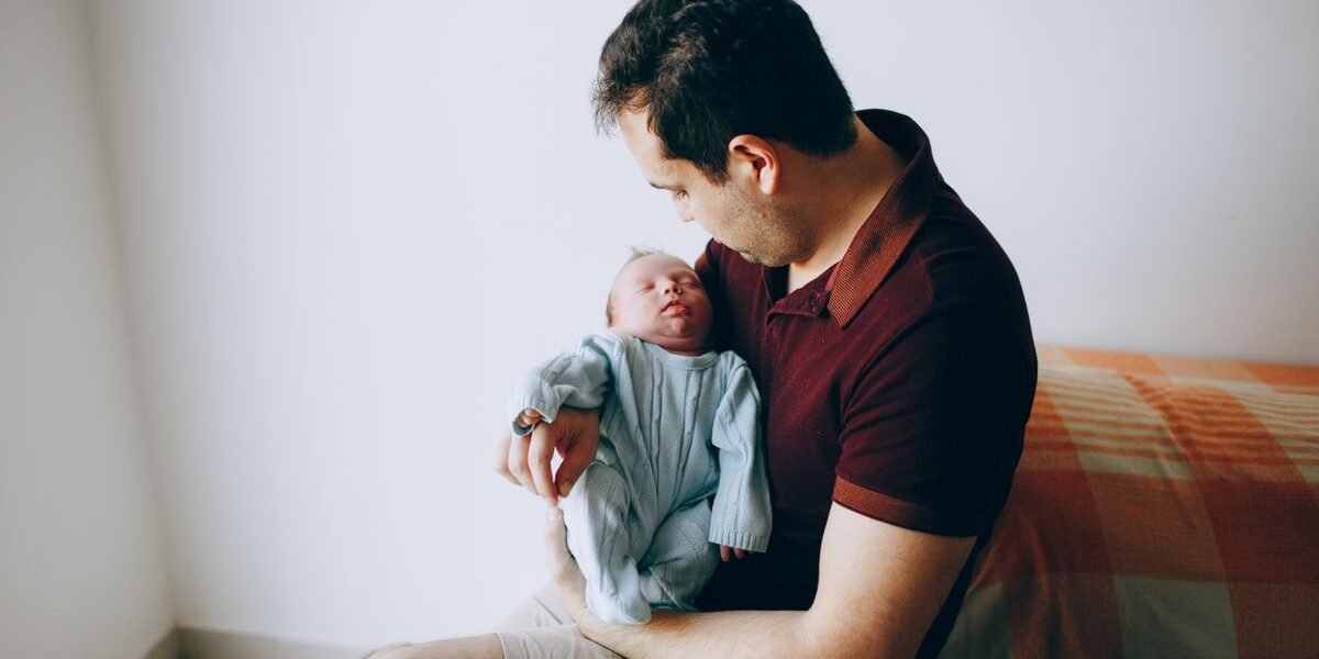 Papa met slapende baby in de armen, blij met een kraamcadeau voor papa