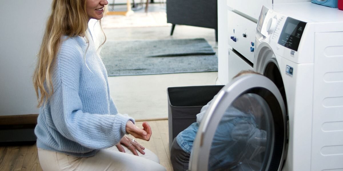 Moeder en kind bij de wasmachine, babykleding apart wassen