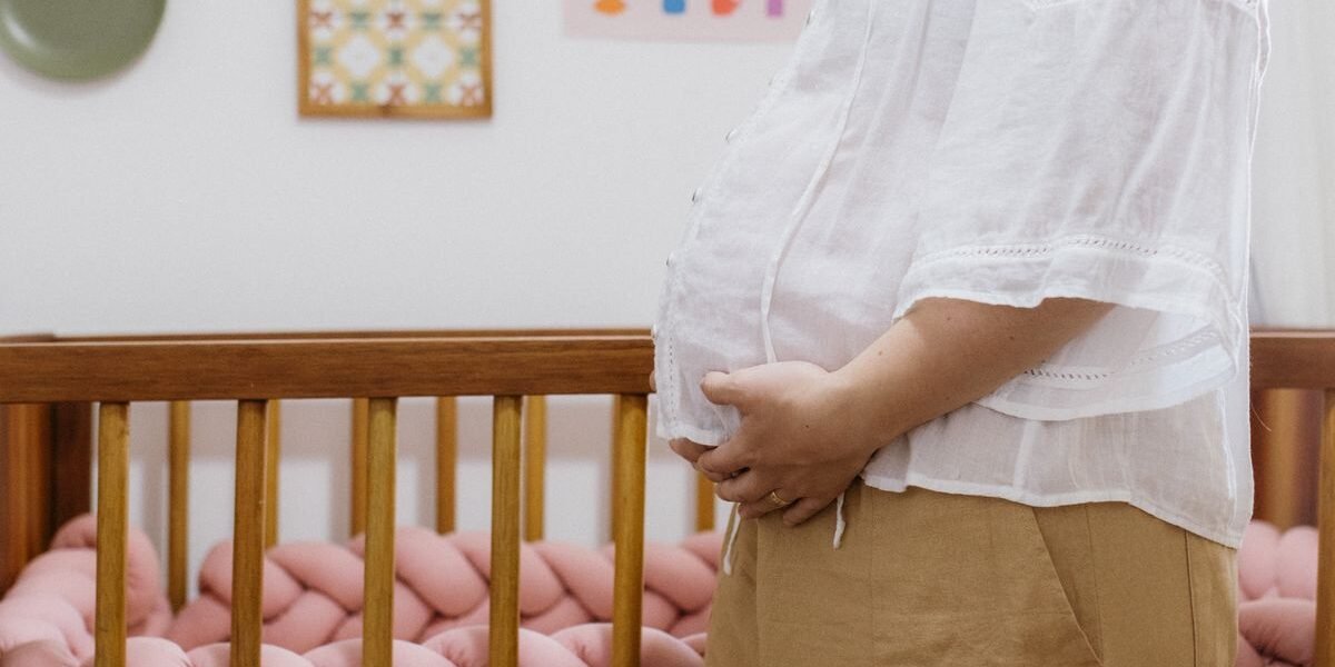 Zwangere vrouw bij het ledikant: wanneer de babykamer inrichten