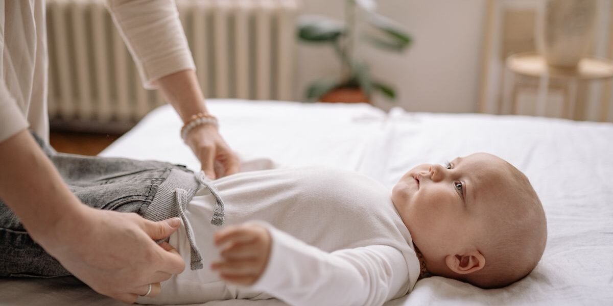 Moeder kleedt pasgeboren baby aan en controleert of de babykleding klein valt