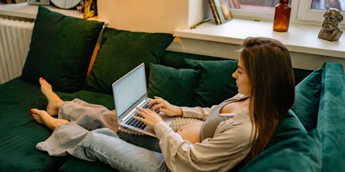 Zwangere vrouw schrijft een welkomsttekst voor haar babylijst op laptop